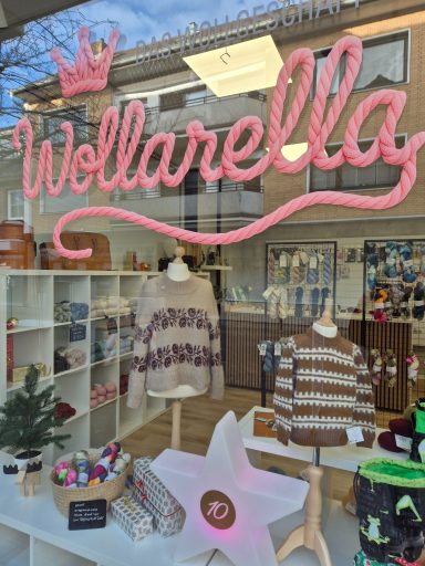 Schaufenster von Wollarella mit gestrickten Pullovern und bunten Accessoires.