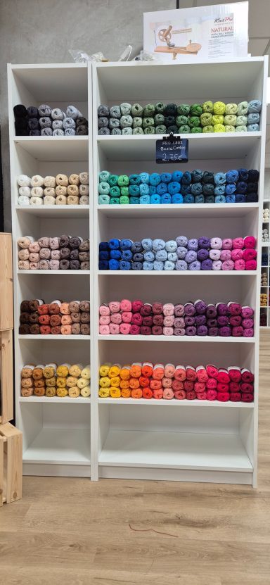 Regal mit ordentlich angeordneten Garnknäueln in verschiedenen Farben.