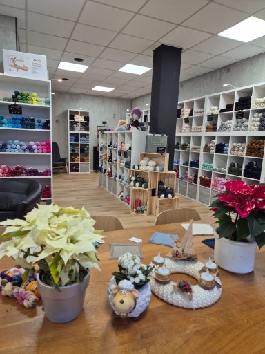 Ein Laden mit Wolle und Handarbeitsmaterial, Blumen auf einem Tisch im Vordergrund.